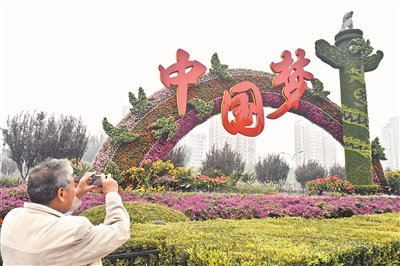 2013年9月30日，一名行人在北京复兴门桥拍摄“中国梦”主题花坛。（资料图片）