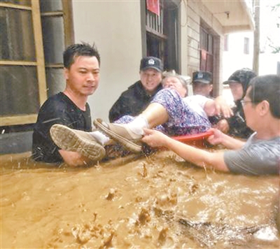受台风“利奇马”影响,8月10日下午,安徽省宁国市宁墩镇老街受到洪水侵袭,当地村干部和干警正在将一位被困家中的老人转移到安全地带。李晓红 摄