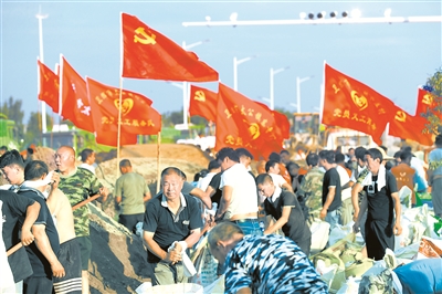 图为2021年7月27日,河南省卫辉市基层党员干部与专业救援队伍、志愿者一起排涝筑堤。 (图片来源:人民视觉)