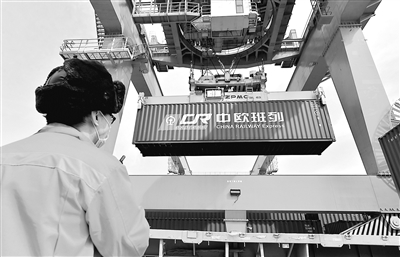 3月11日，一列满载服装、电子配件、电器等50车货品的列车驶出西安新筑车站，开往德国曼海姆，标志着2020年中欧班列（西安）去程班列发送车数突破1万车。图为工人在西安新筑车站货场指挥吊运中欧班列集装箱。 新华社发（唐振江 摄）