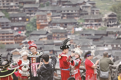 近年来,贵州省雷山县不断推动高铁资源和旅游景区深度融合,方便各地游客前来体验苗族风情,观赏苗寨美景,为古老苗寨的乡村振兴注入活力。图为今年国庆假期,游客穿着民族服装在该县西江千户苗寨观景台拍照留念。新华社发(林世康 摄)