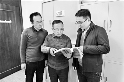 图为韩锡才（中）正在与同事们研究相关案情。尹琦琦 摄