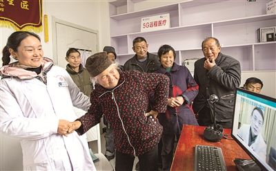 地处大别山腹地的安徽省金寨县大湾村率先在全省开通5G远程医疗会诊功能，住在深山的农村群众可及时享受到优质的医疗服务。图为该村村民在村医的帮助下向5G远程医疗会诊专家讲述病情。新华社发（陈力 摄）