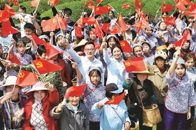 江西省德兴市香屯街道办江村千亩茶园,两名基层扶贫干部挥舞着党旗,和大家一起唱起了《唱支山歌给党听》。 (图片来源:视觉中国)
