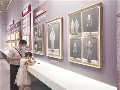 图为“民族复兴的百年旗帜——中国历史研究院征集海外中共珍稀文献展”现场，小观众在革命先烈遗照前写下参观感言。  本报记者 聂新鑫 摄