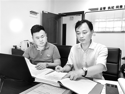 图为肖鹰（右）正在查阅相关案件资料。