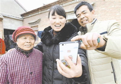 图为帮扶责任人淮安市涟水县保滩镇财政所干部(中)走访贫困户,现场打开“阳光扶贫”APP填写帮扶项目食用菌种植收入信息。曹政 摄