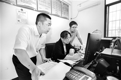 图为施昌年（左）在办案中调阅相关资料。